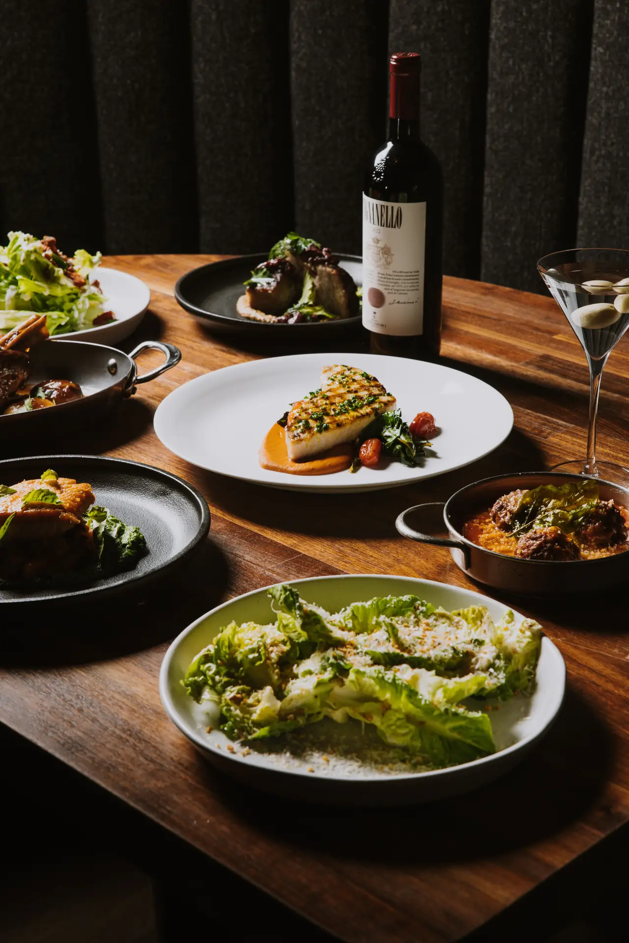 Steak, pasta and salads shared across a table with red wine